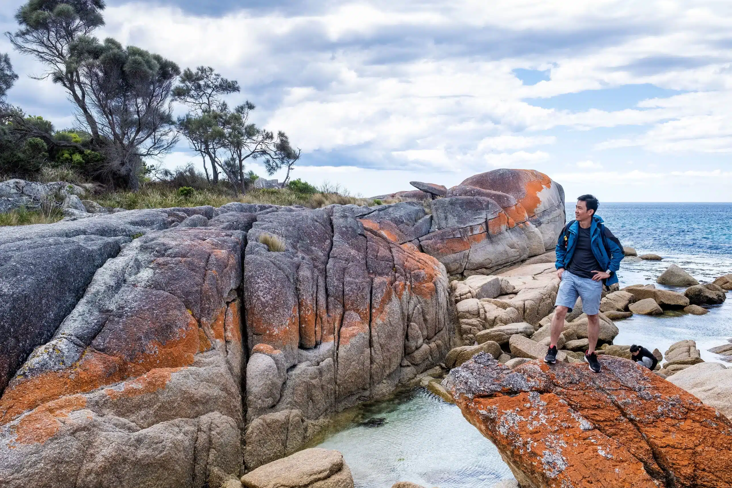Tasmania’nın vahşi doğasında bir adam, kamp ateşi başında doğanın büyüleyici manzarasıyla poz veriyor. Tasmania'nın vahşi doğasında bir adam, kamp ateşi başında doğanın büyüleyici manzarasıyla poz veriyor.